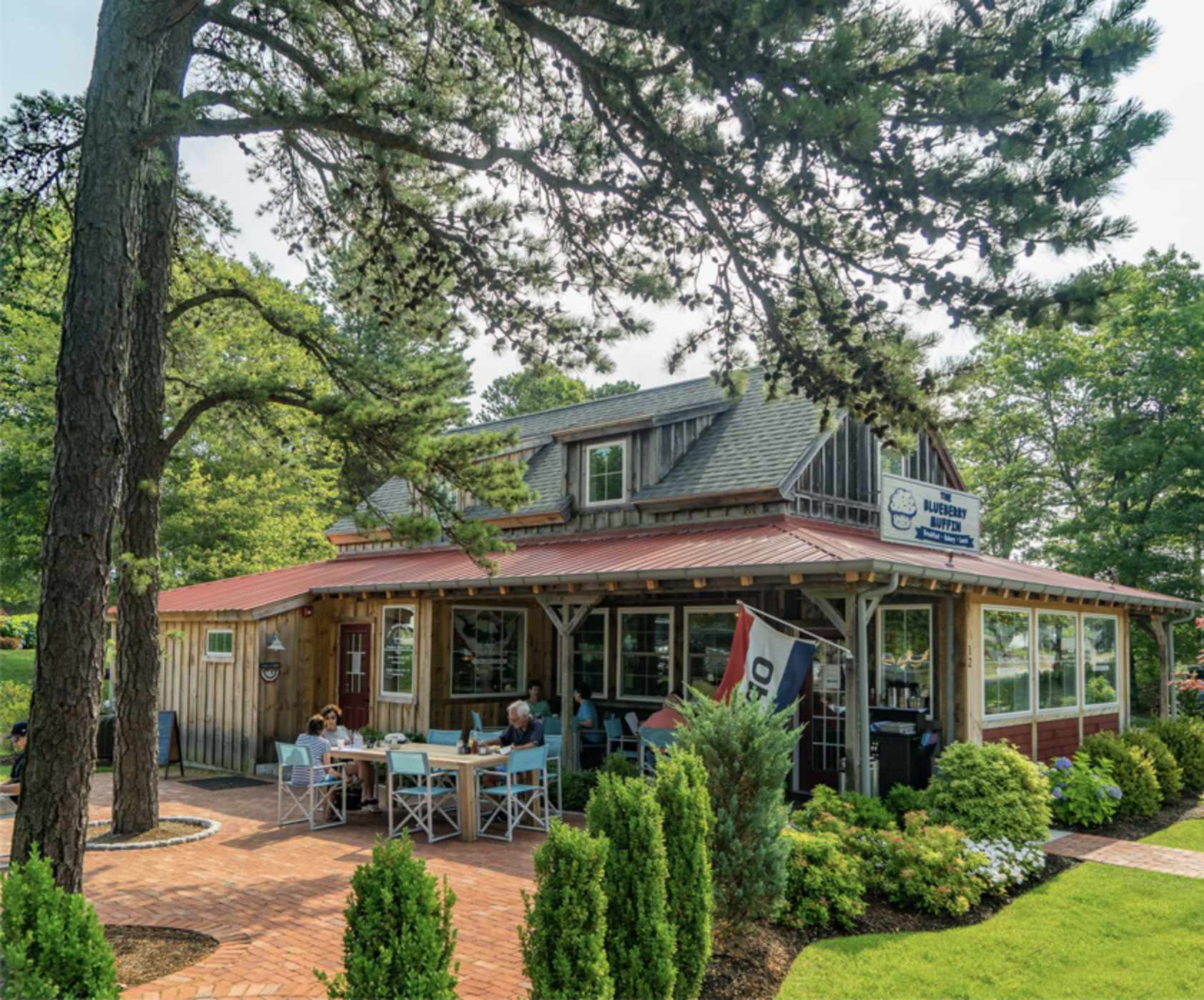 old shingled house with red covered patio and an outdoor picnic table